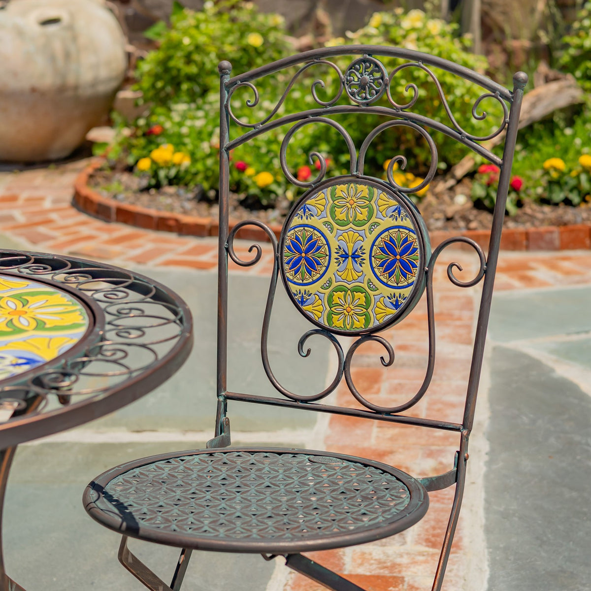Ornate bronze-toned chair with a colorful mosaic back and patterned metal seat beside the matching table.