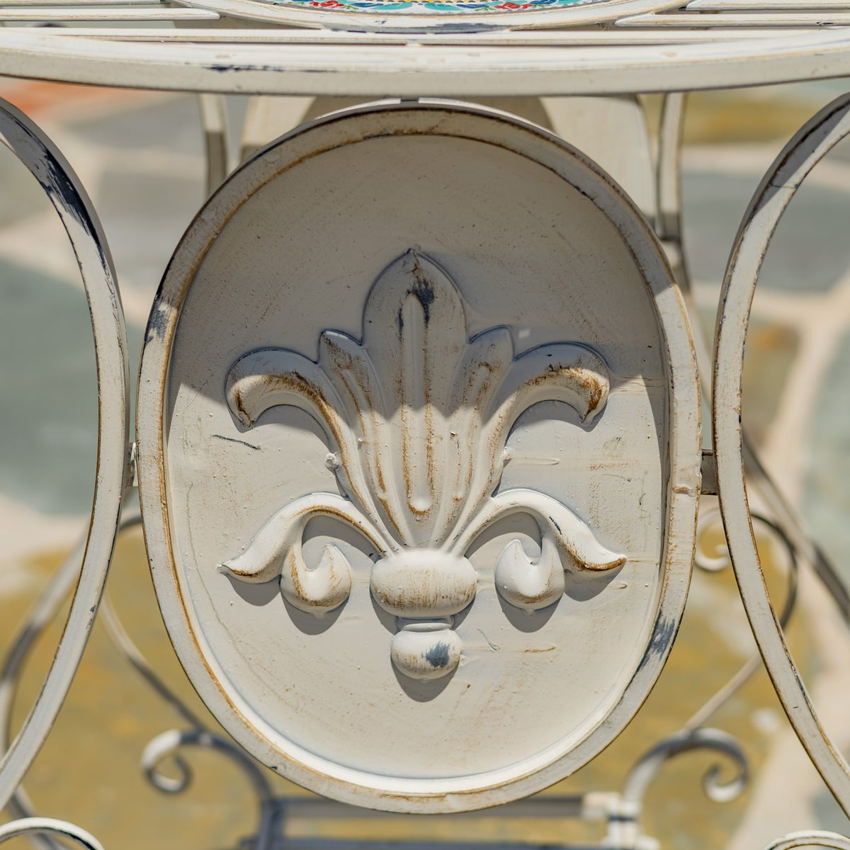 Close-up of an ivory oval side panel with raised floral ornament and distressed edges.