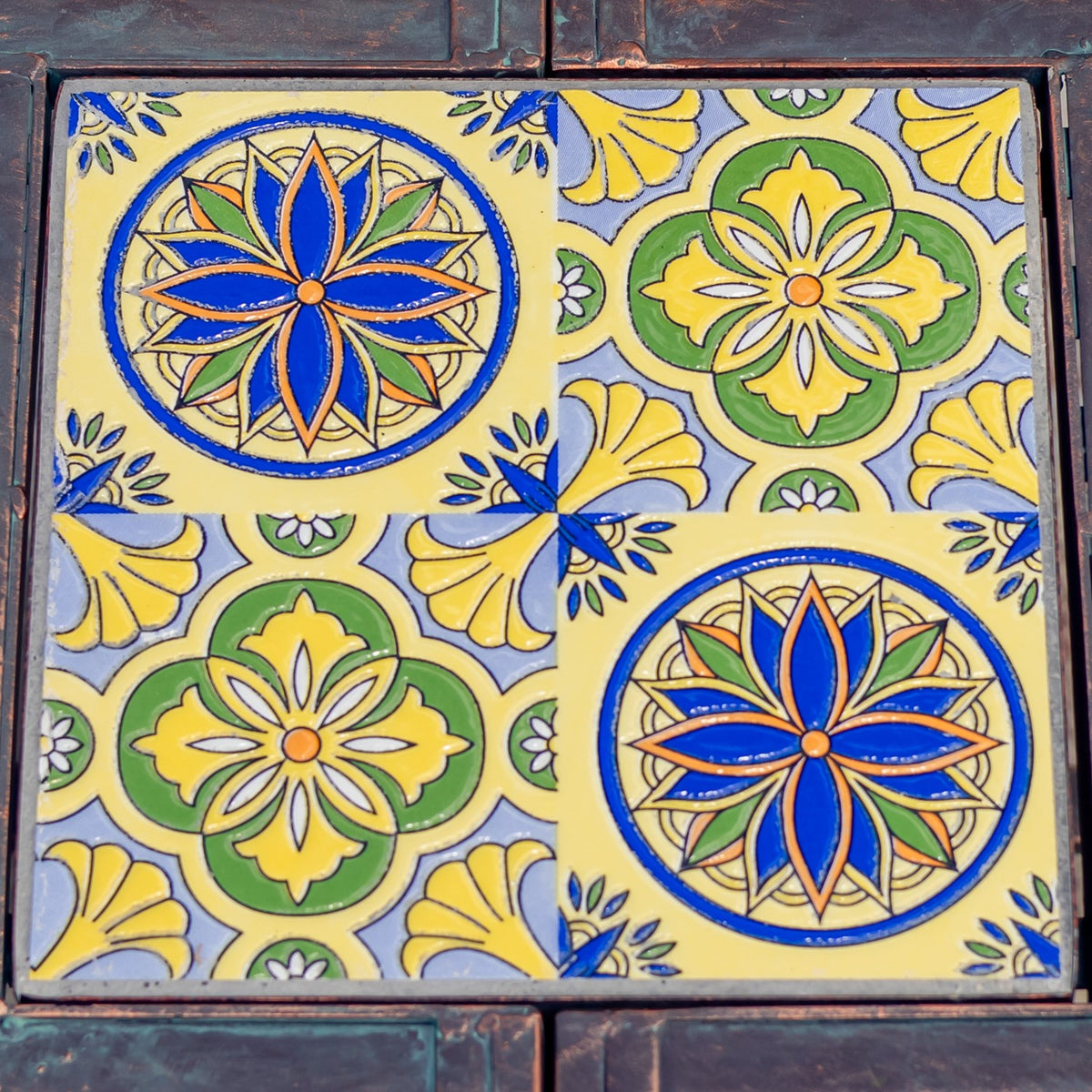 Close-up of colorful square mosaic tiles with blue, yellow, green, and orange floral patterns.