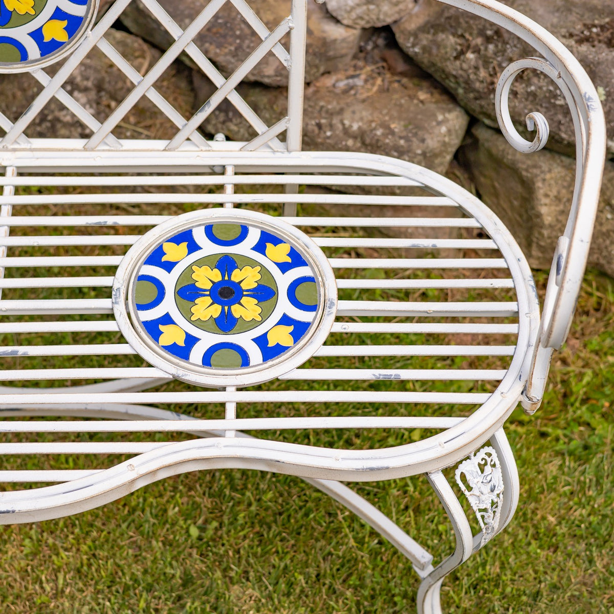 Close-up of the white metal bench seat with a blue and yellow mosaic inset.