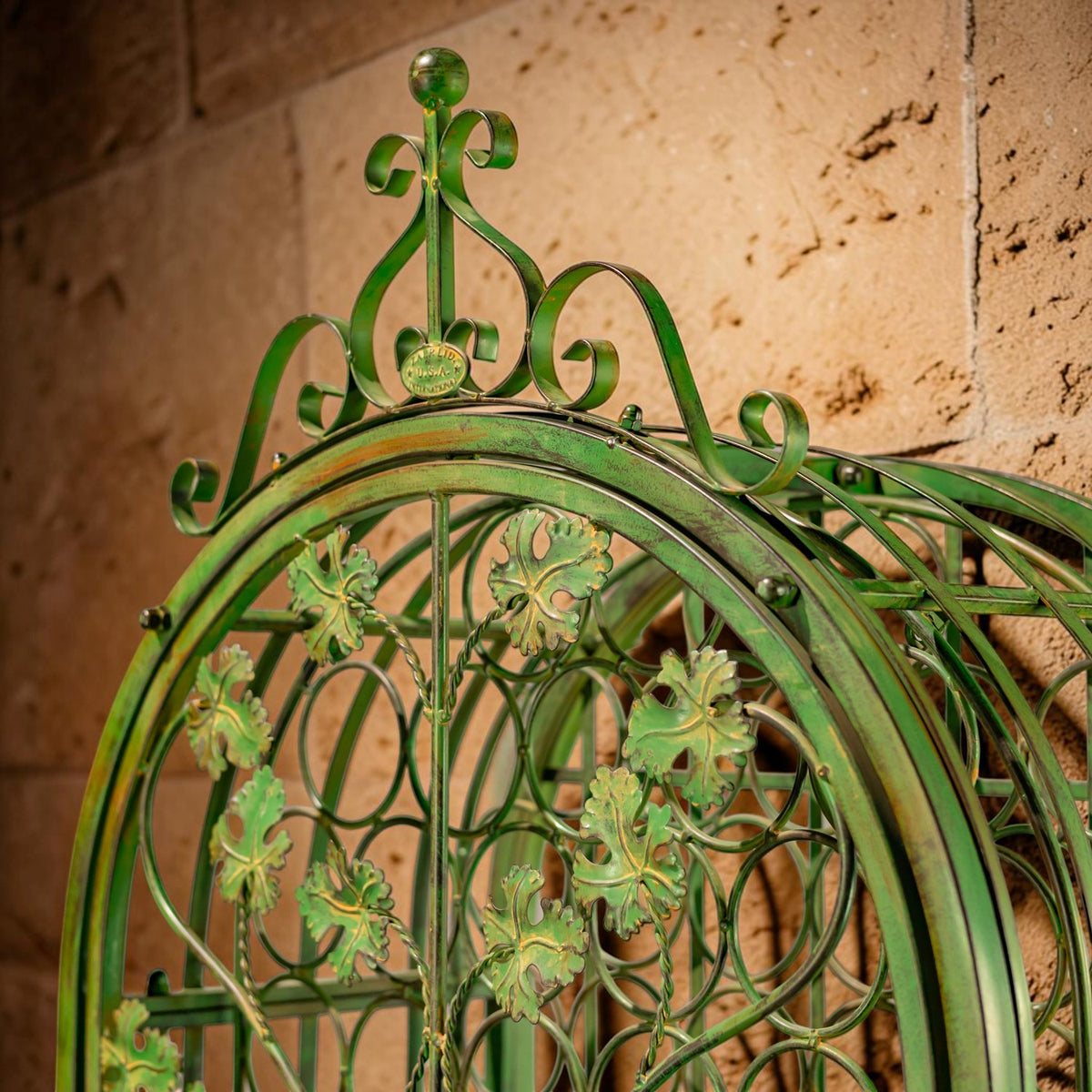 Close-up of the cabinet’s ornate green iron crown with curled scrollwork and leaf decorations.