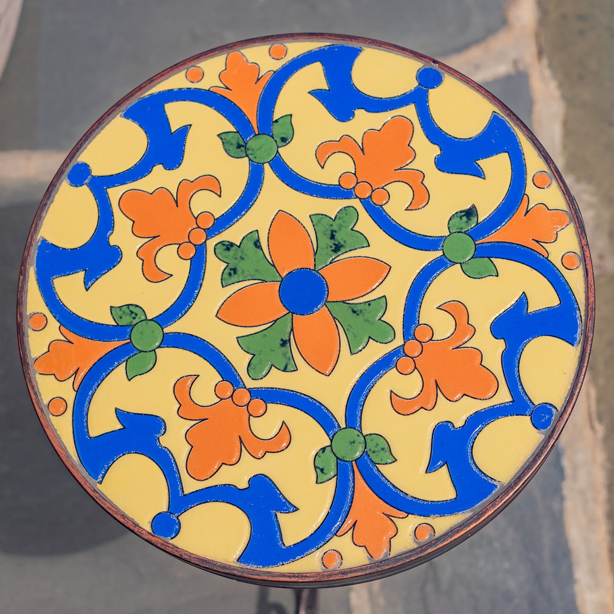 Round tabletop with a colorful blue, orange, green, and yellow floral mosaic pattern.