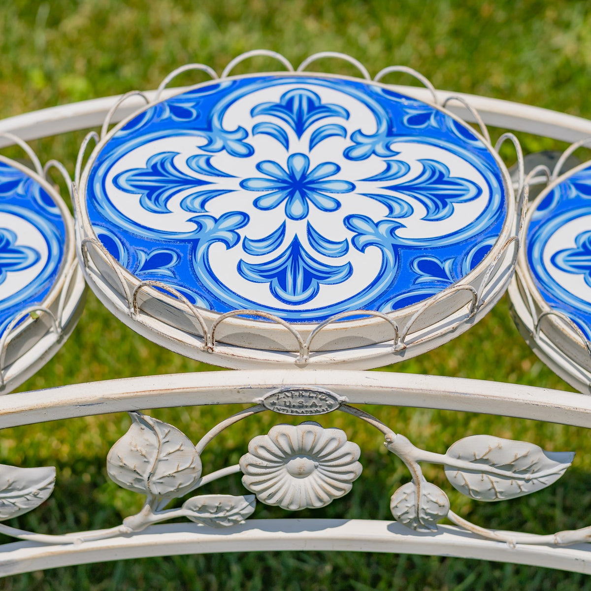 Blue-and-white patterned mosaic tray surrounded by an antique-white metal rim with floral scrollwork.