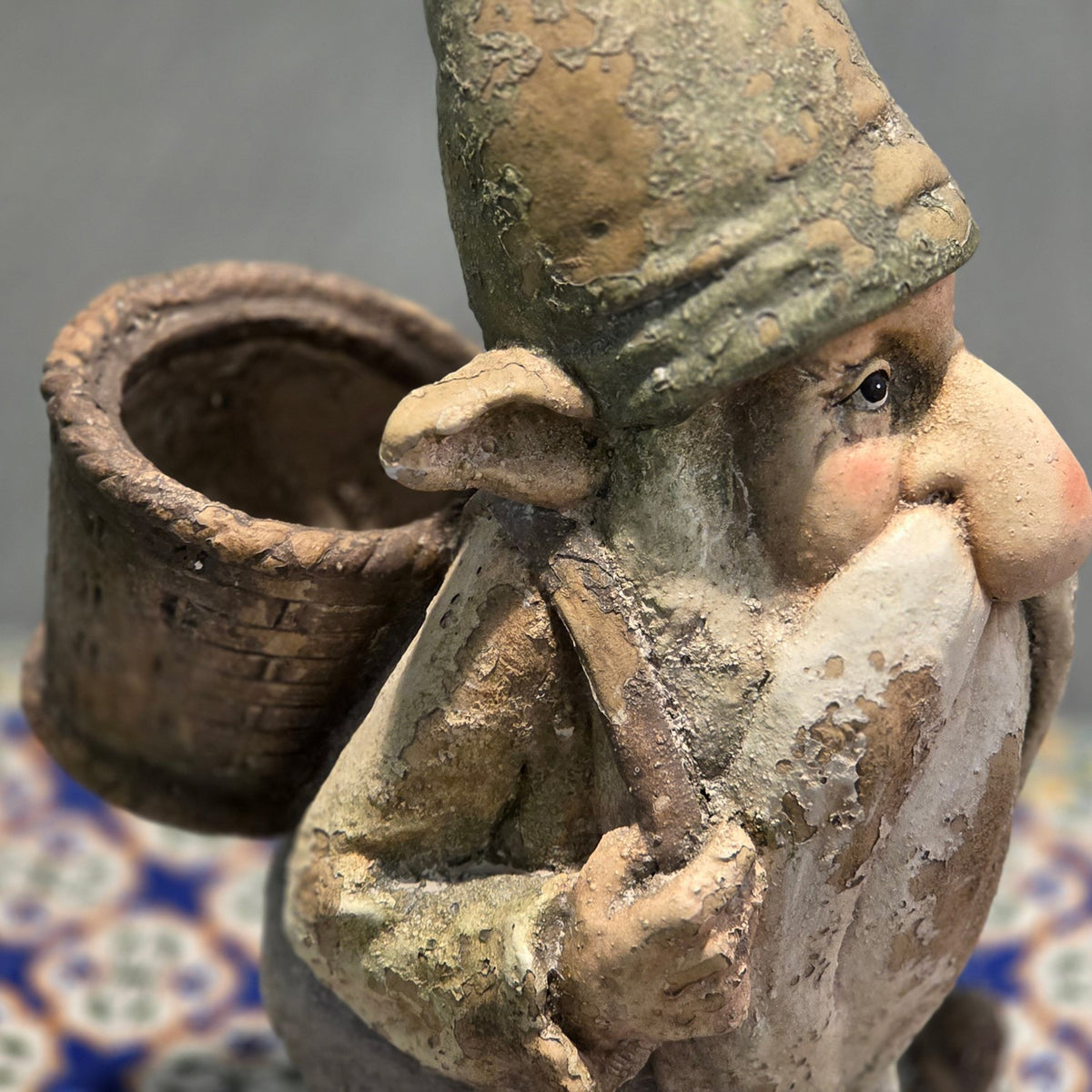 Close side view showing the gnome's face and the open basket planter on its back
