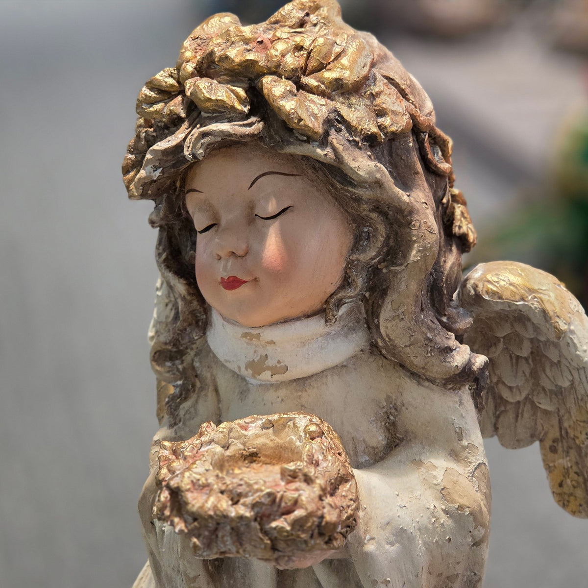 Front close-up of angel figurine with closed eyes and bouquet of flowers