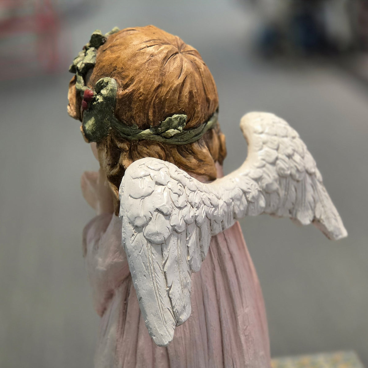 Angled rear view highlighting the angel's white wings and holly crown