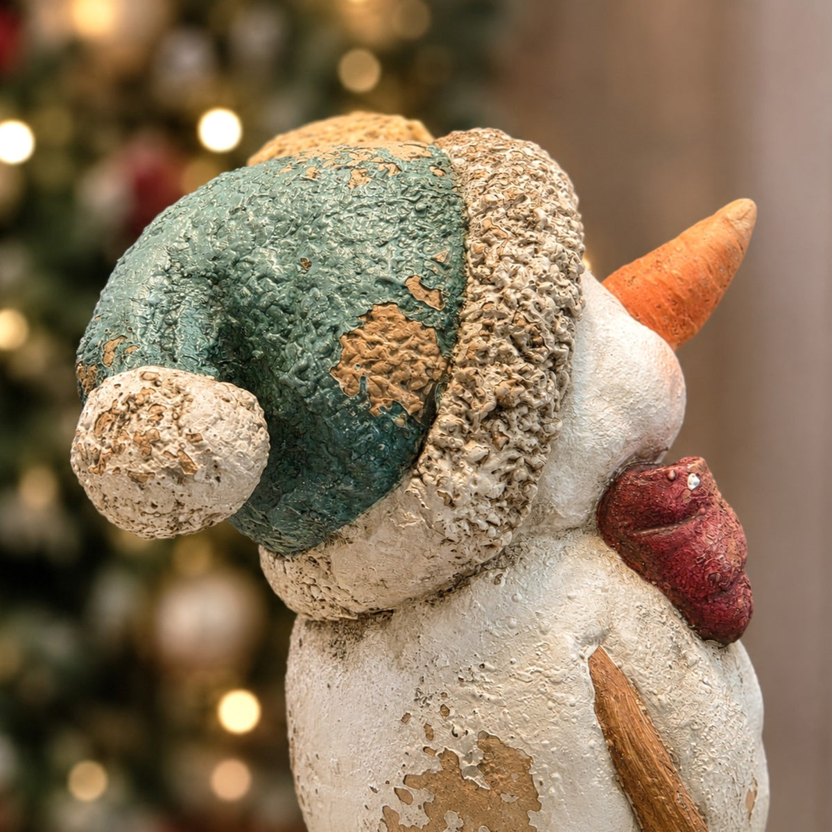 Close-up of the snowman's textured green cap and scarf from the side