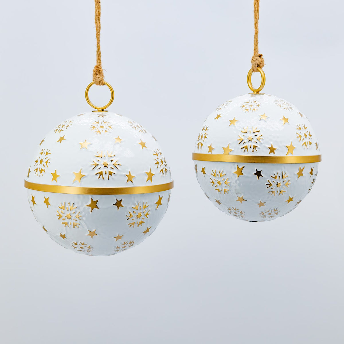 Two white hanging baubles with gold snowflake and star cutouts, shown at different sizes.