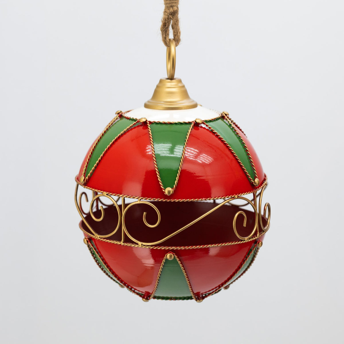 A red and green ornament hangs against a pale background, showing its decorative gold filigree band.