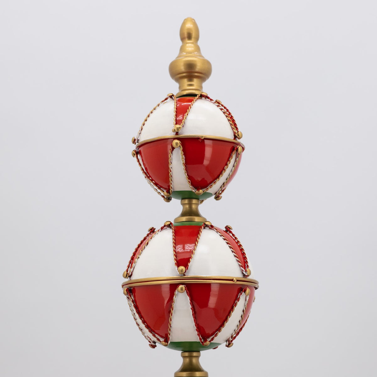 Tall ornament tower with two glossy red-and-white baubles, green accents, gold trim, and a gold finial.