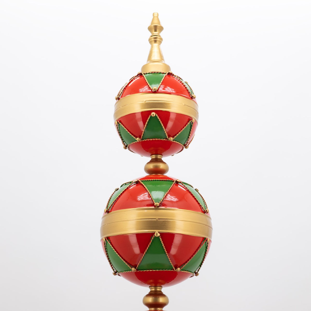 Two red and green ornament globes with gold bands stacked on a decorative gold finial.