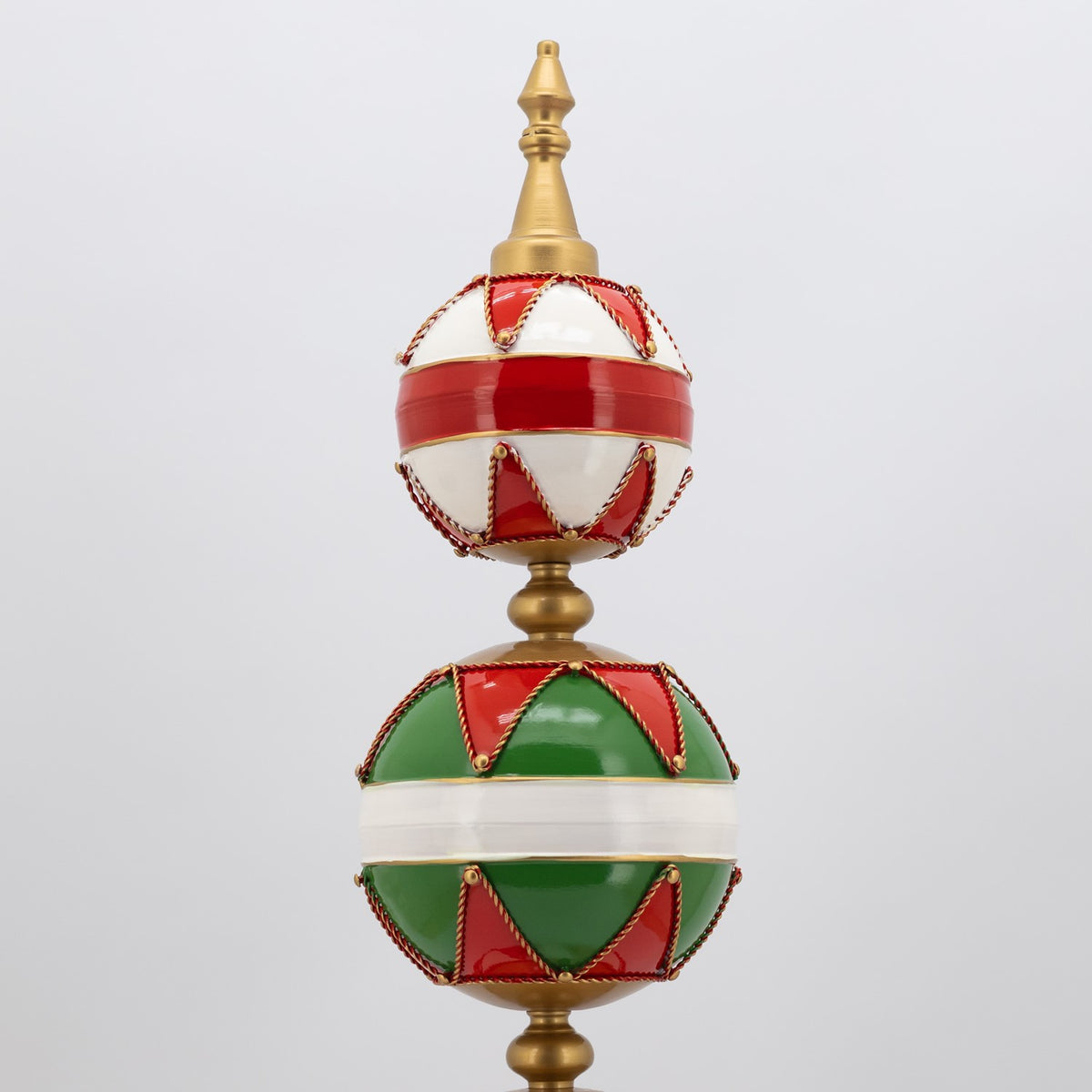 A tall ornament tower with stacked red, green, and white spheres and a gold finial.