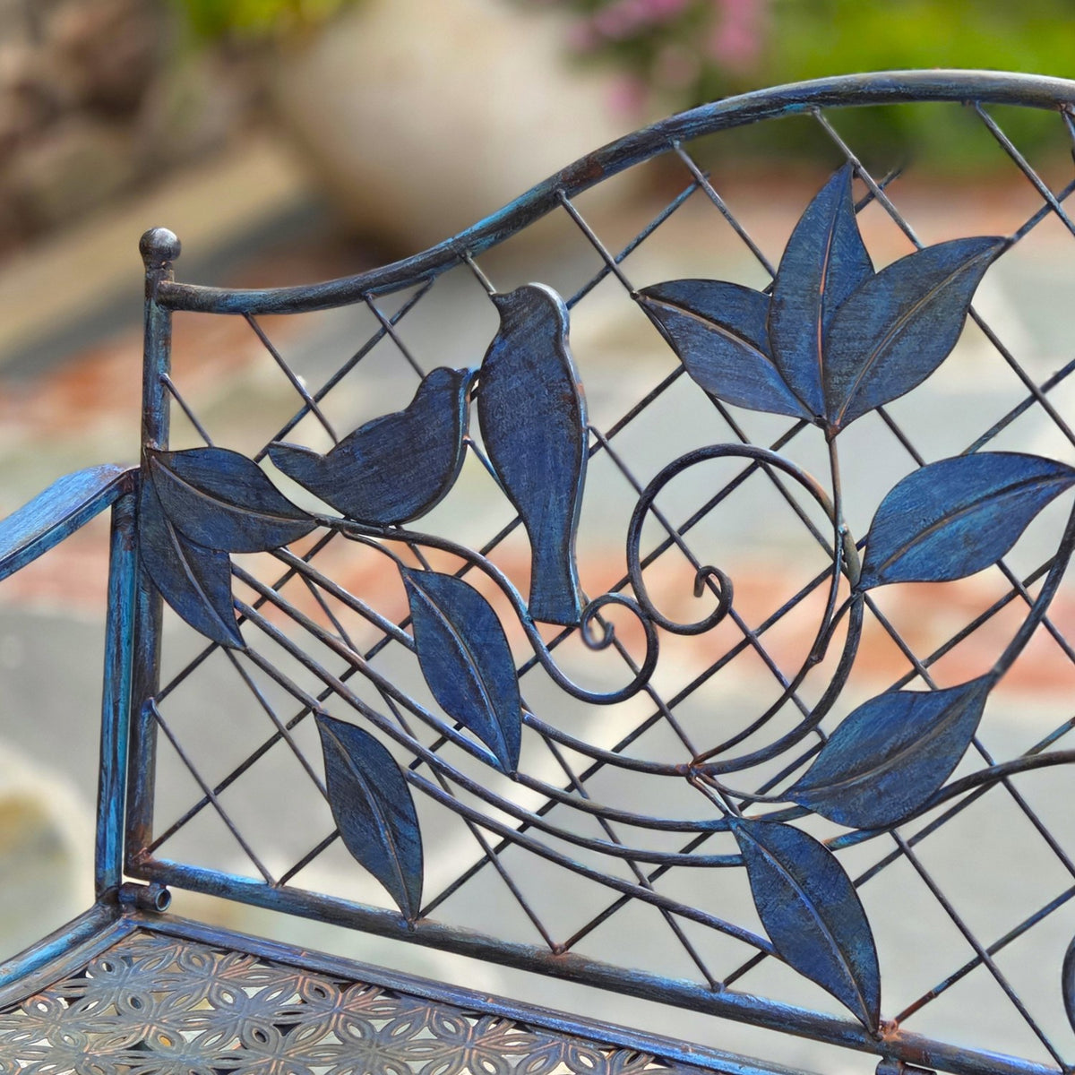 Close view of the bench’s metal bird, leaf and curling vine decorations.