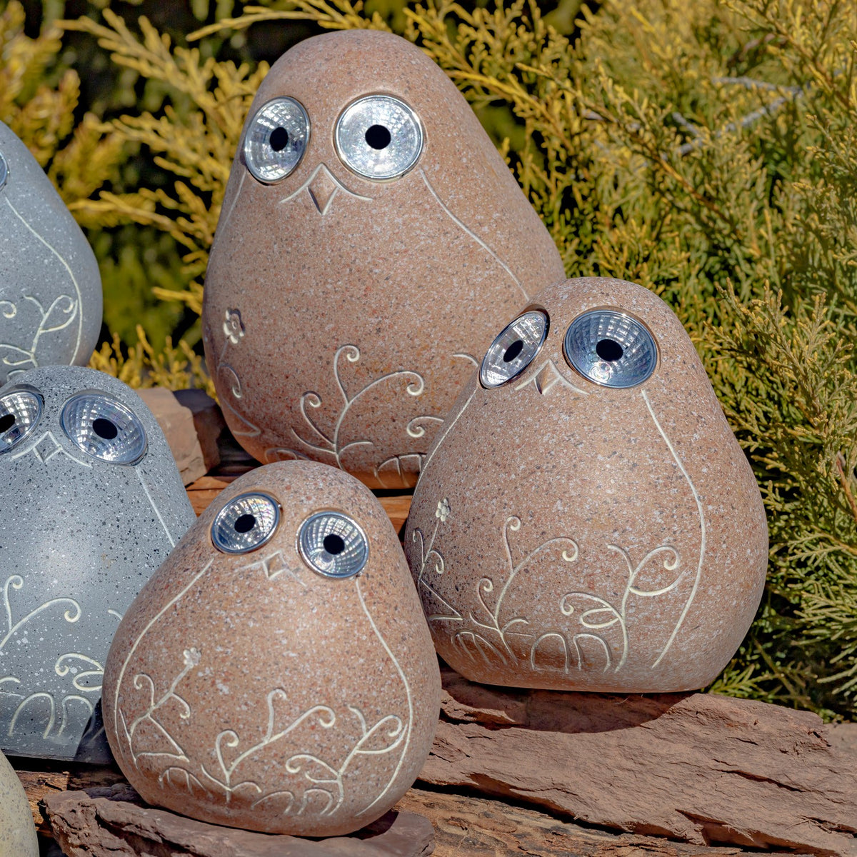 Three tan stone-look birds with etched floral patterns and reflective eyes sit among partially visible gray birds.