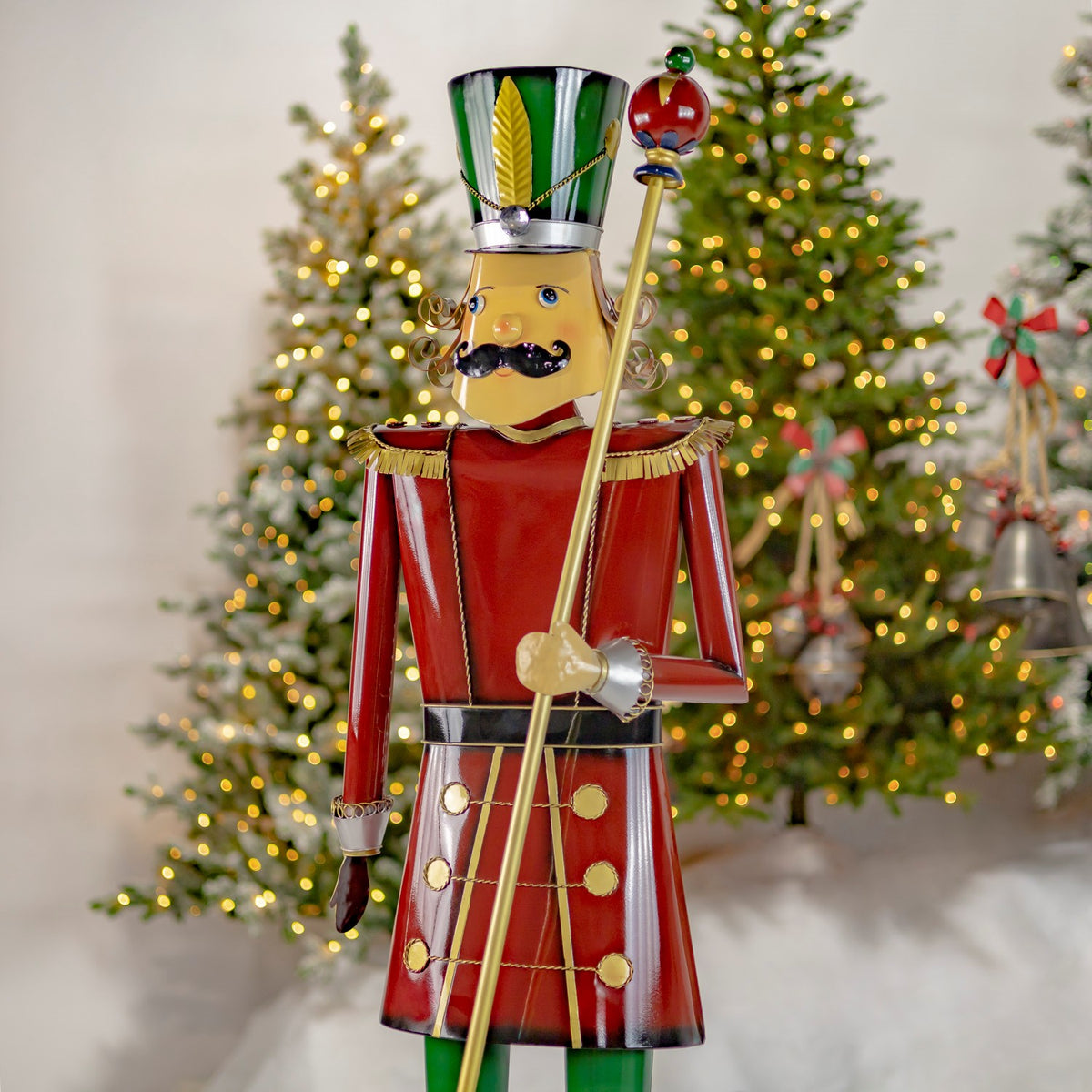 Three-quarter view of the full burgundy and gold nutcracker holding a baton by a tree