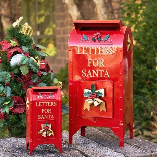 Glossy red mailbox pair with Santa lettering and gold accents beside outdoor greenery