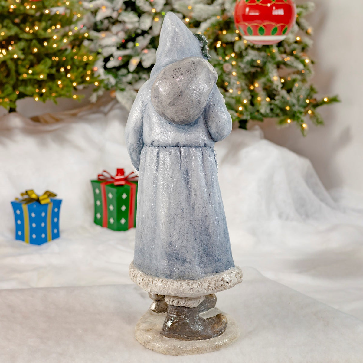 Rear view of the blue-gray hooded Santa statue with a bag over one shoulder