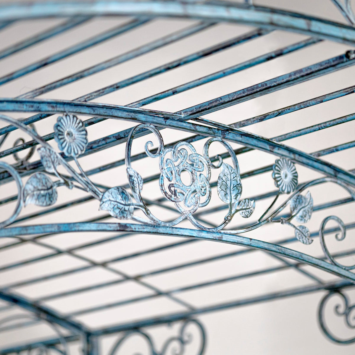 Blue-gray metal roof bars above a decorative band of curled vines, leaves, and flower motifs.