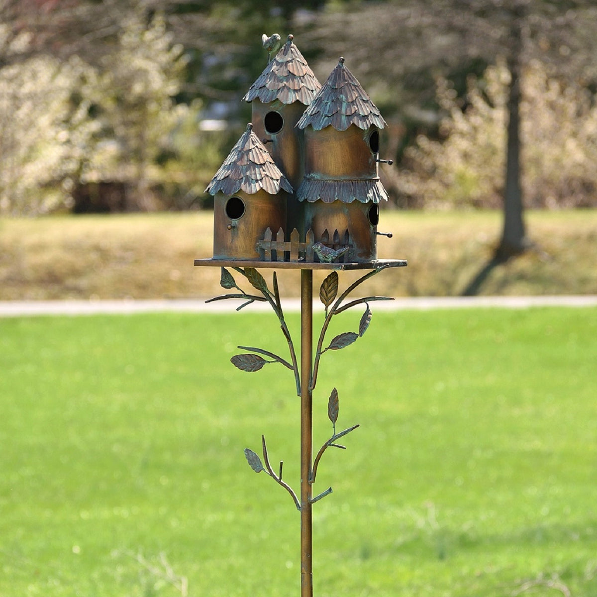 Closer view of three peaked birdhouses with round openings and leaf-shaped metal accents.