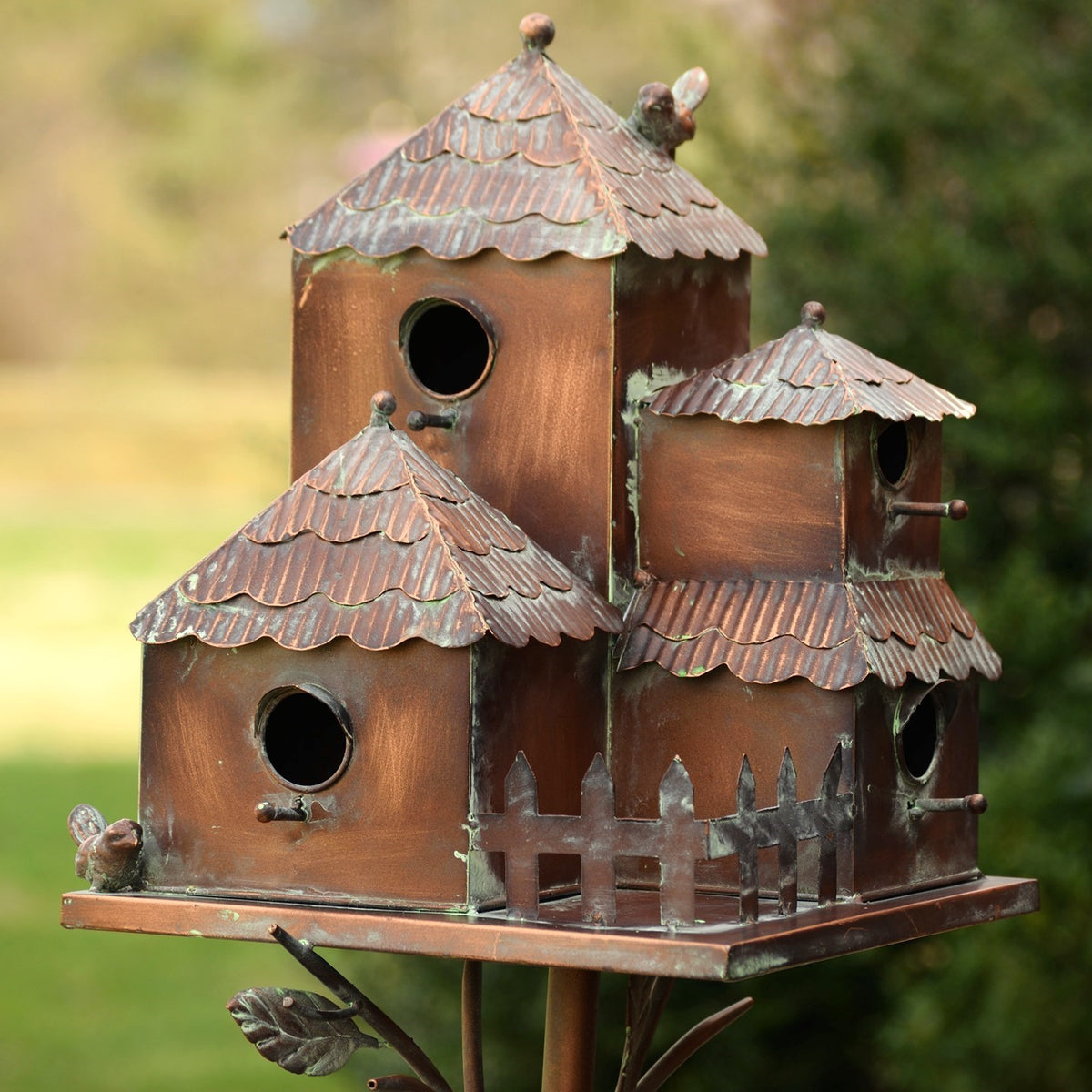 Closer view of the brown birdhouse cluster, showing round openings, layered roofs, and a small fence.