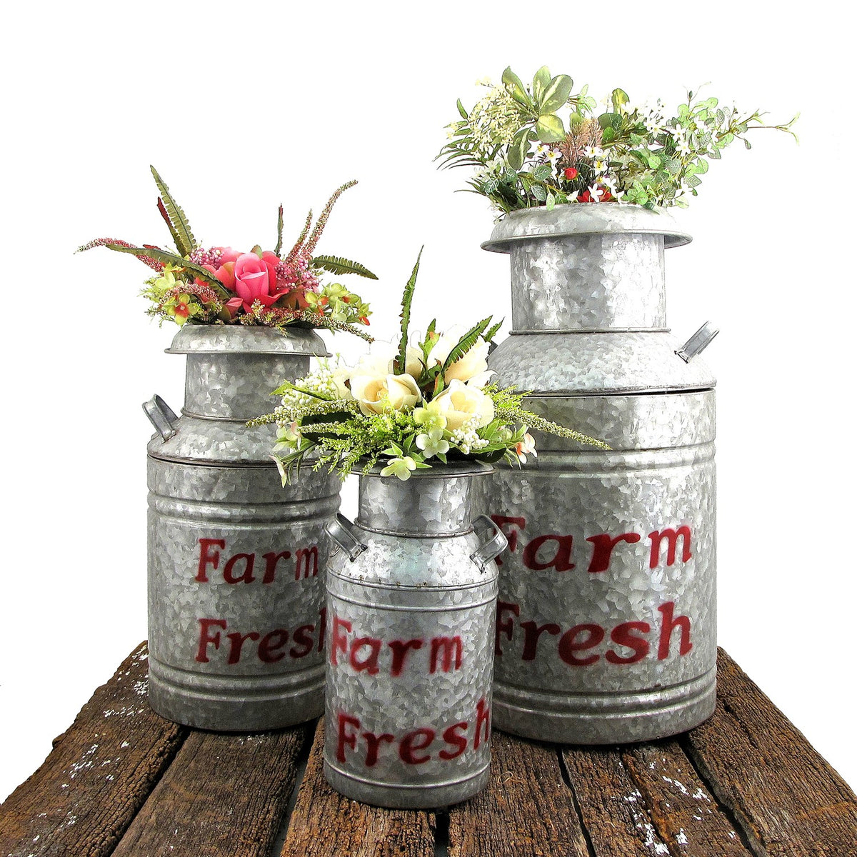 Three galvanized milk-jug planters displayed with colorful flowers against a white background.