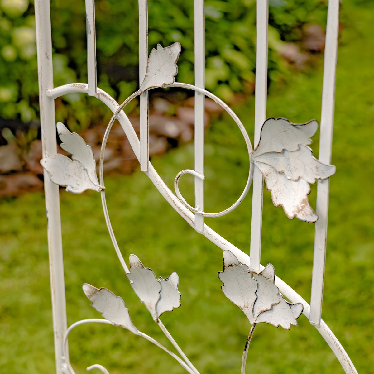 Close-up of the arch’s pale metal scrollwork with raised leaf ornaments.