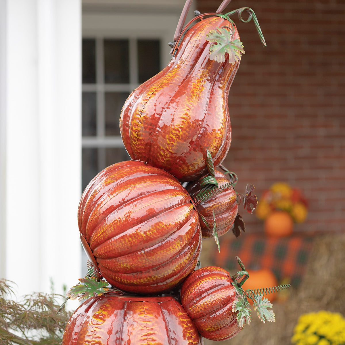 Angled view of stacked orange pumpkins, including a tall pear-shaped pumpkin and smaller side pumpkins.
