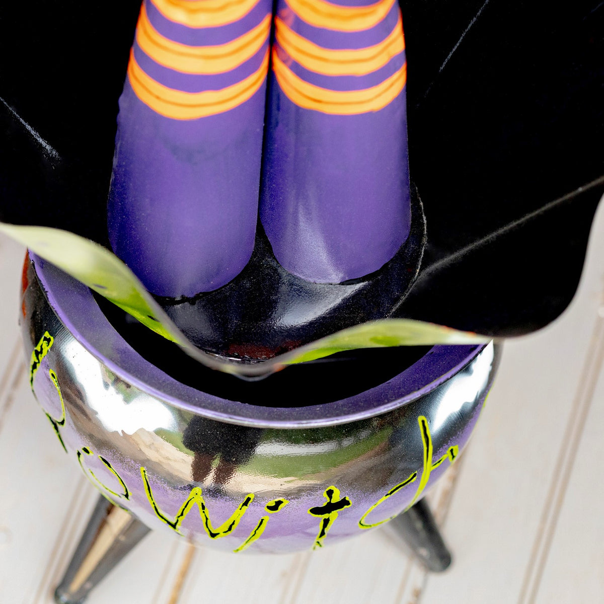 Overhead close-up of striped witch legs inside the open cauldron