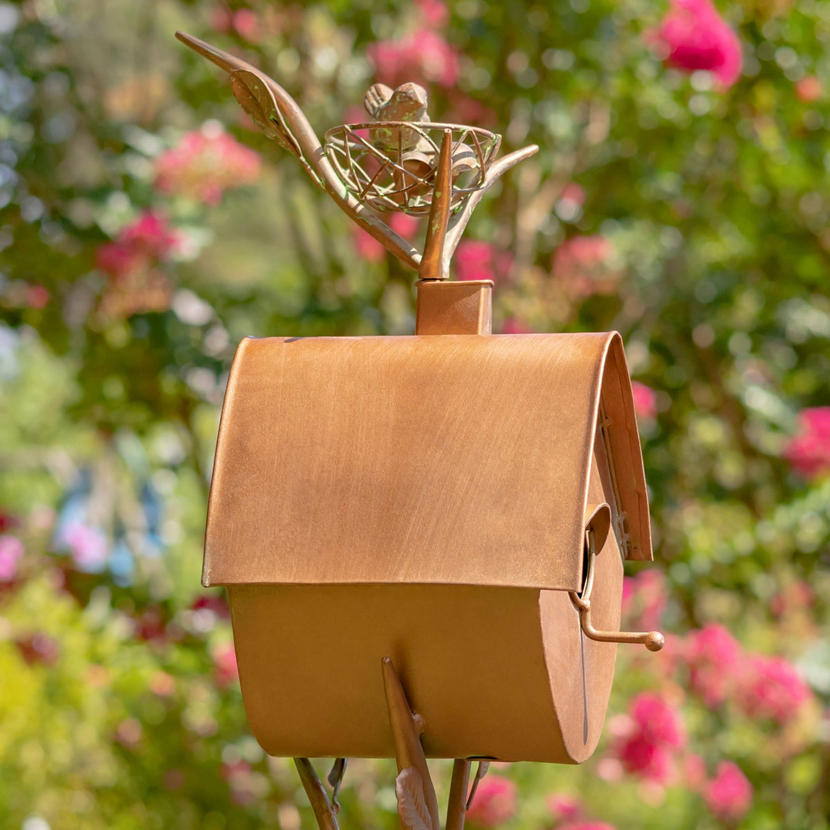 Close view of the rounded birdhouse body, curved roof, side latch, and decorative nest above.