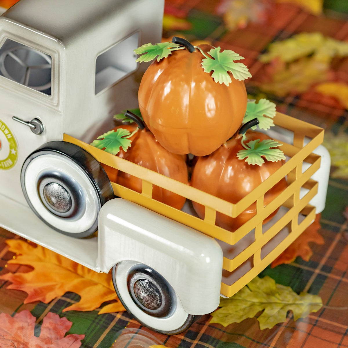 Close view of orange pumpkins in the truck’s wooden-look bed, with the cab and wheels partly visible.