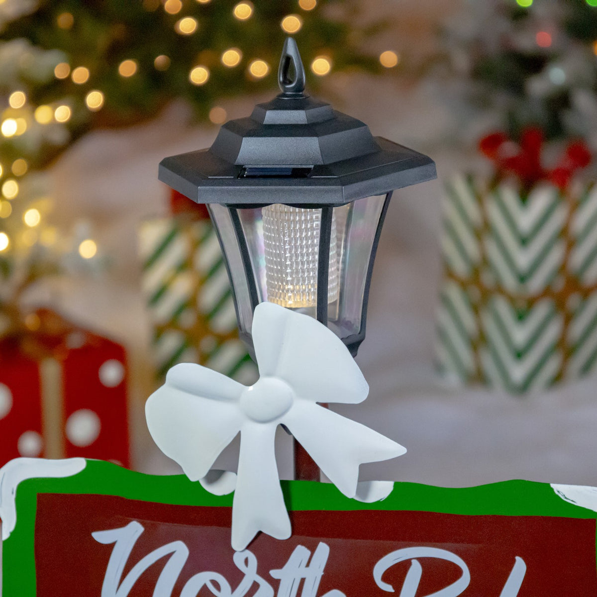 Close-up of the lit lantern and white pinwheel above a cropped green-and-red sign.