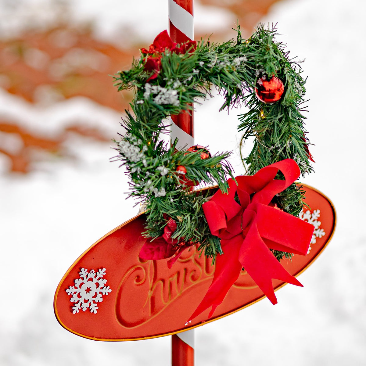 Close-up of the lantern’s red oval plaque, wreath, white snowflake decorations, and large red bow.