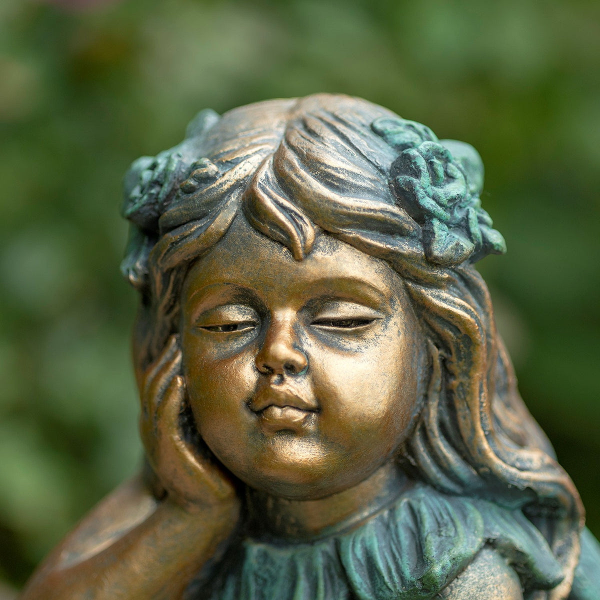 Close-up of the fairy statue’s calm face, wavy hair, and flower ornaments.