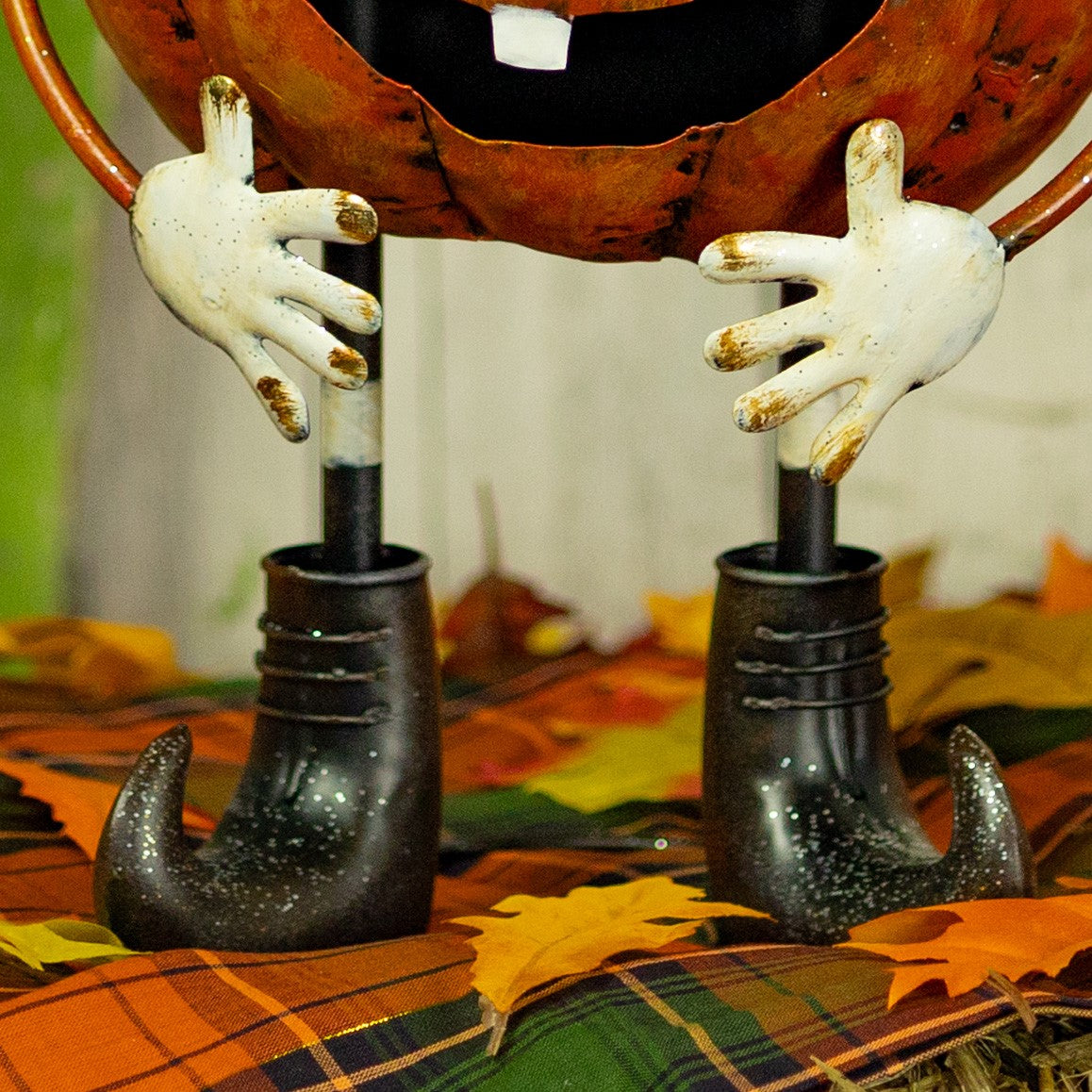 Close view of the pumpkin figurine's white hands and curled black boots