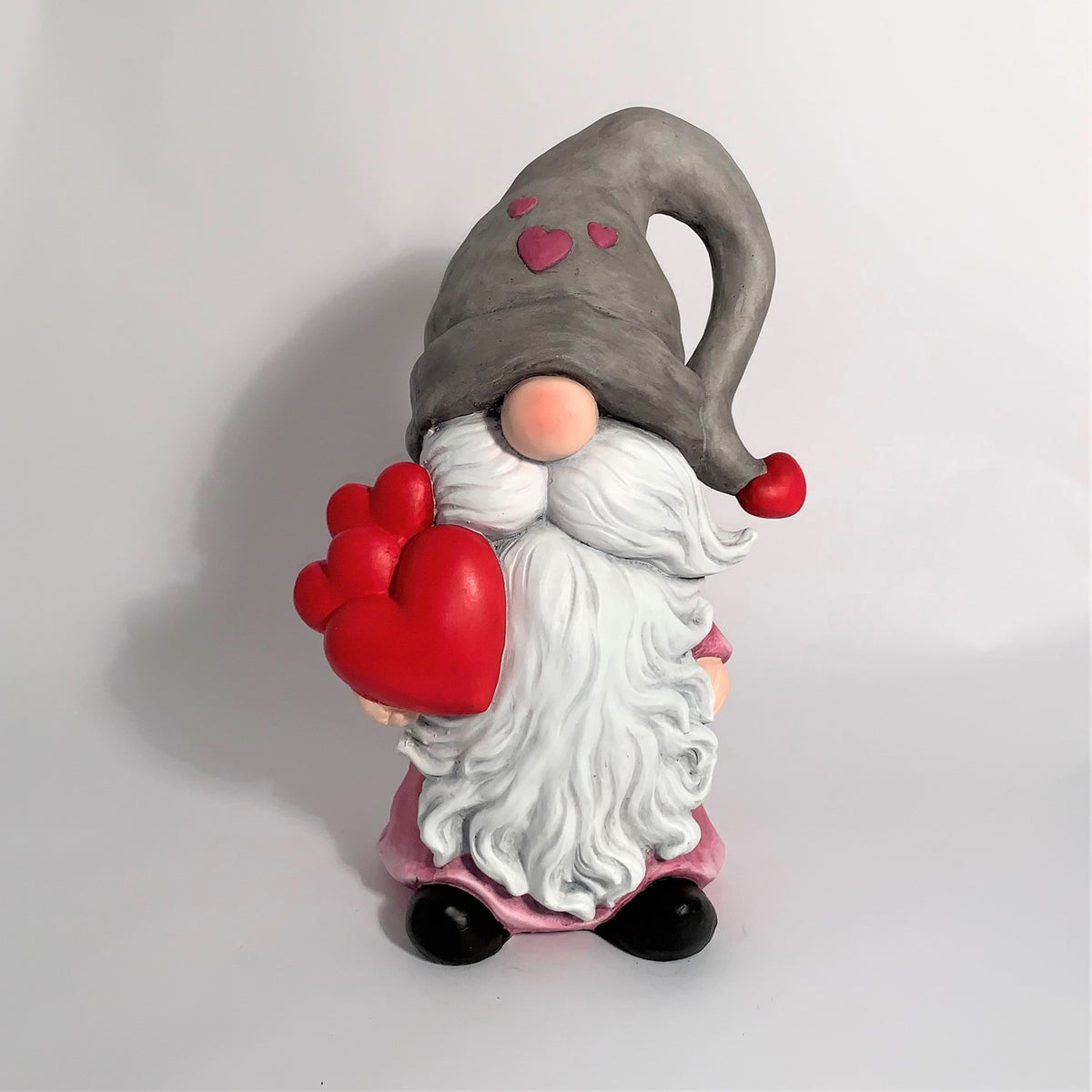 A gnome with a floppy gray hat, pink outfit, white beard and red heart-shaped balloons.