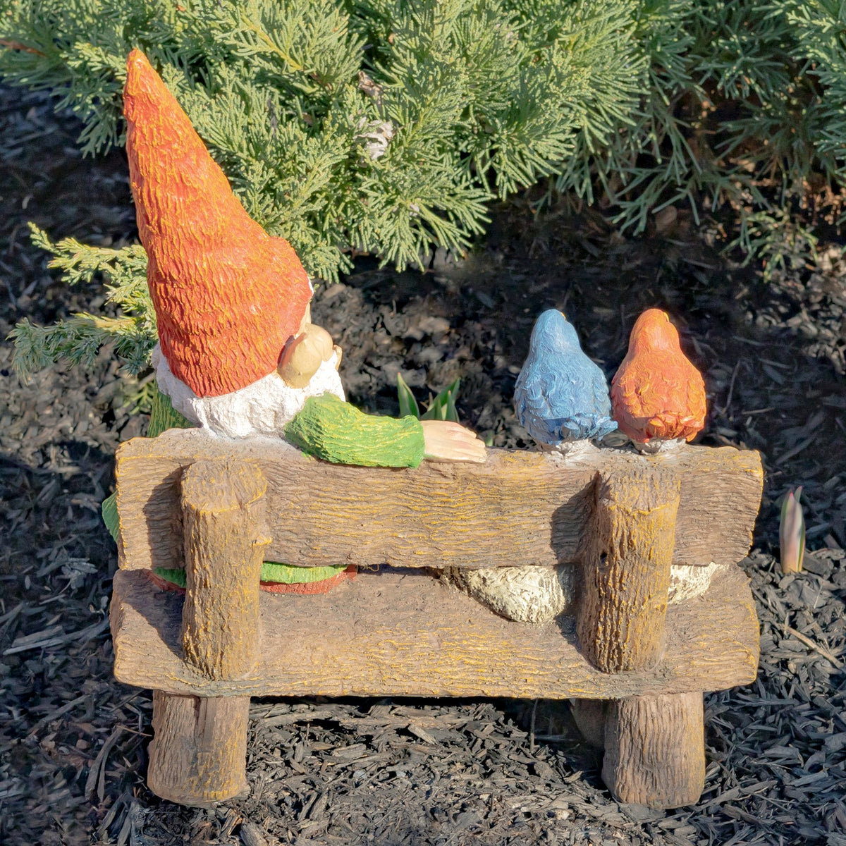 Back of a garden gnome beside two birds perched on a rustic wooden bench.