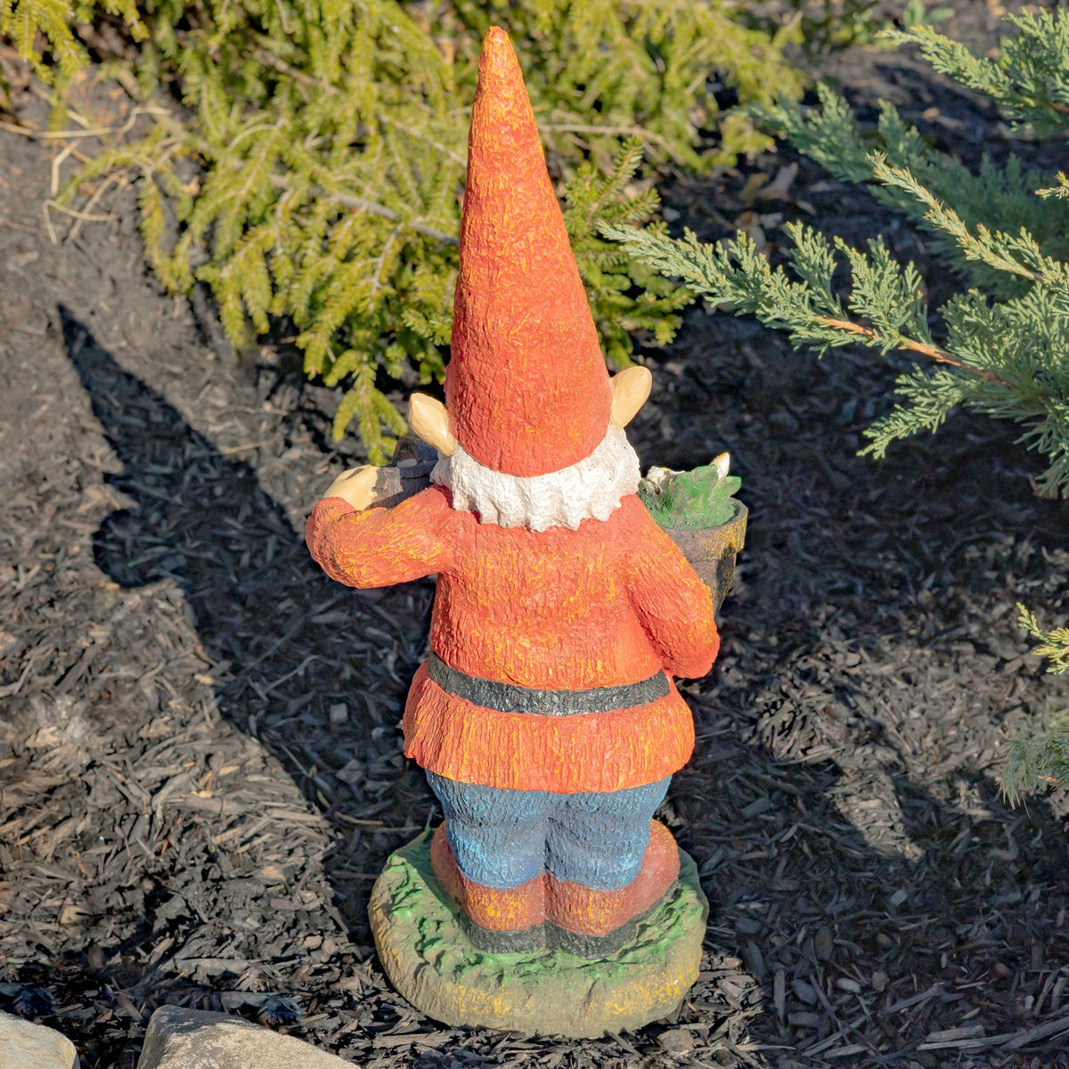 Back of the gnome statue, showing its pointed red hat, red coat, blue pants, and green base.