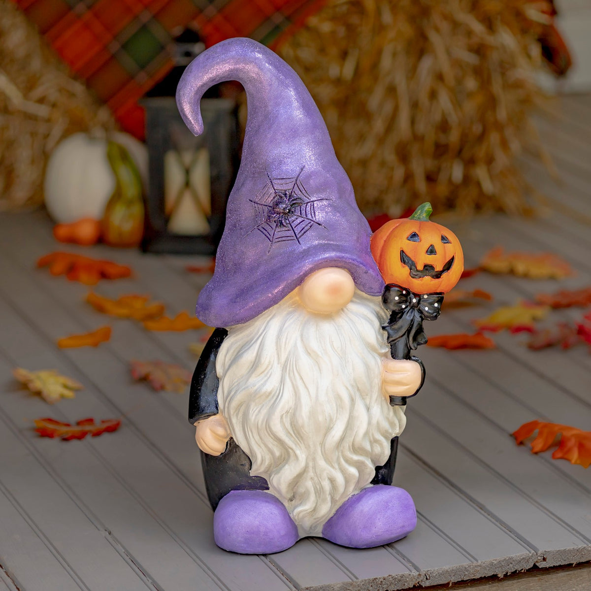 Purple-hatted Halloween gnome holding a small jack-o'-lantern
