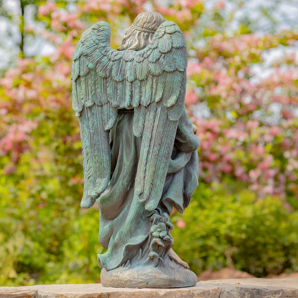 Rear view of the angel statue, showing layered feathers across both wings and the flowing robe.
