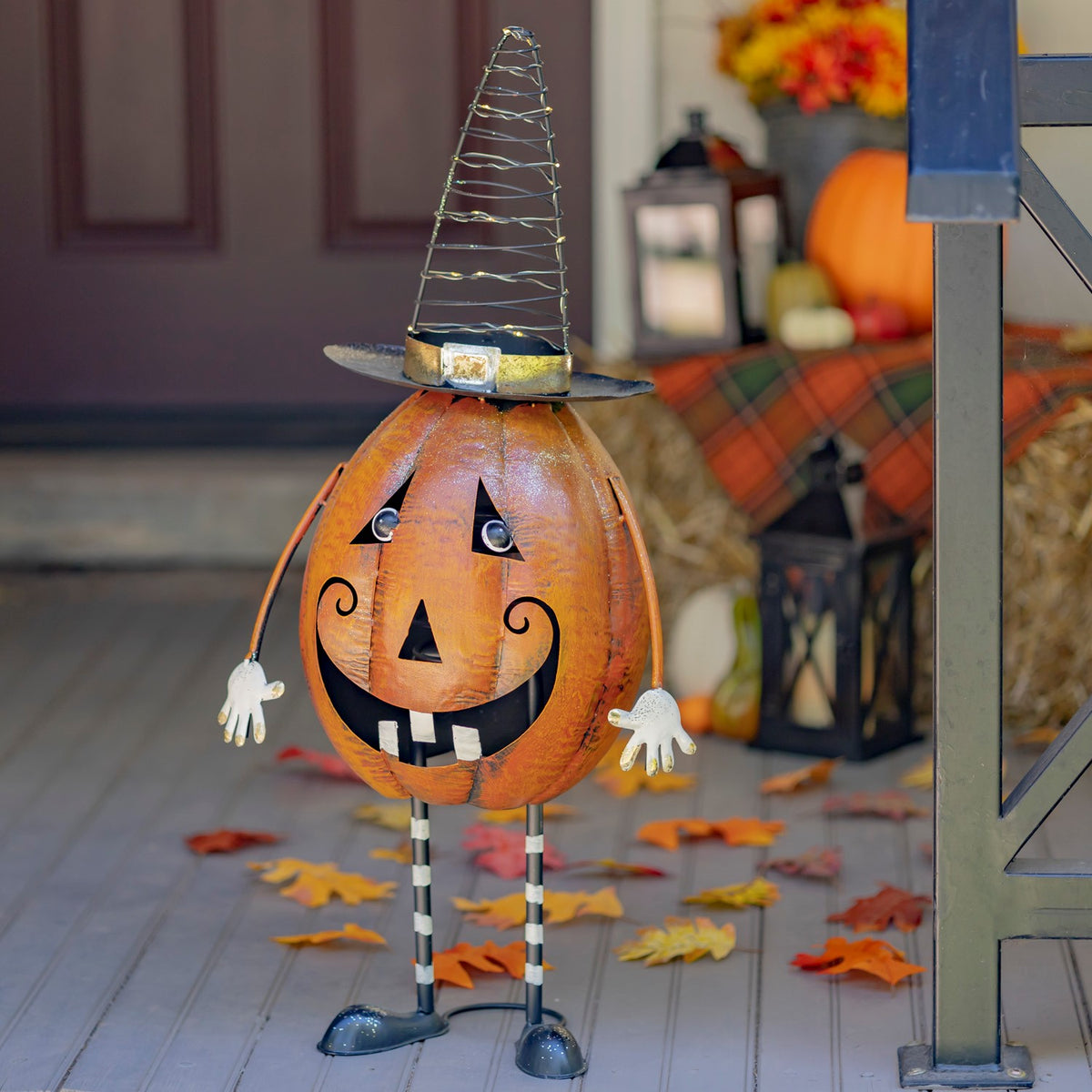 Angled view of the jack-o'-lantern figurine on a porch with autumn decor