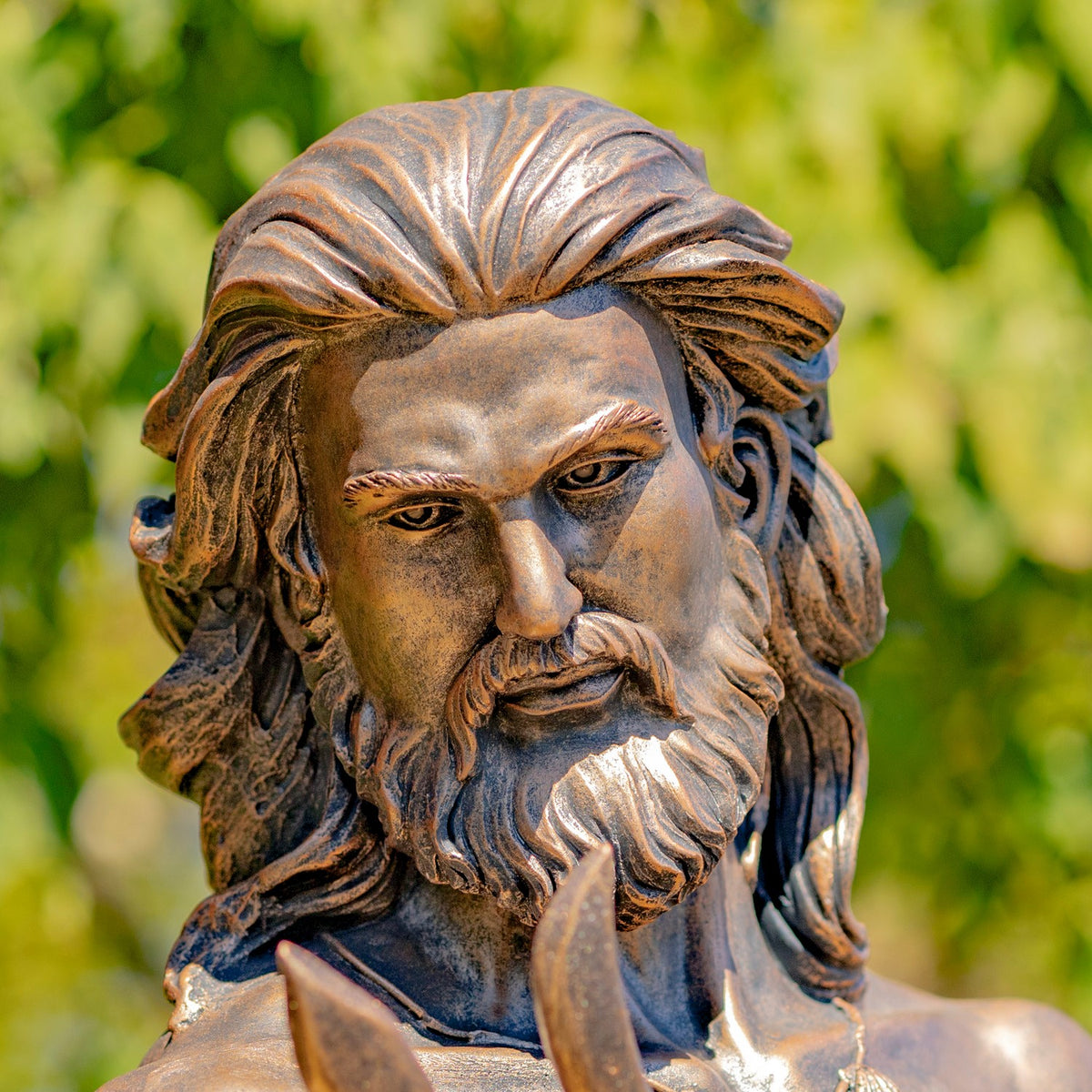 Close-up of the statue’s bearded face and flowing hair, with a trident prong in the foreground.