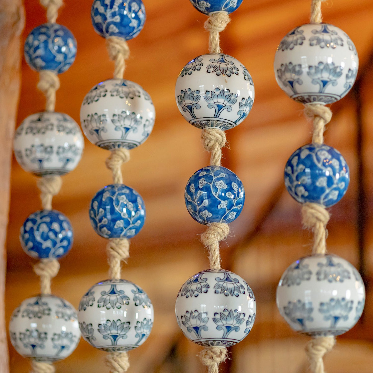 Close view of blue-and-white floral patterns on round ceramic balls threaded along thick rope.