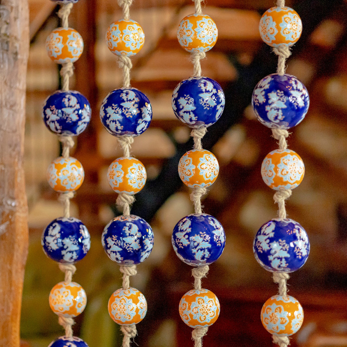 Close view of alternating blue and orange floral-patterned balls tied along jute cords.