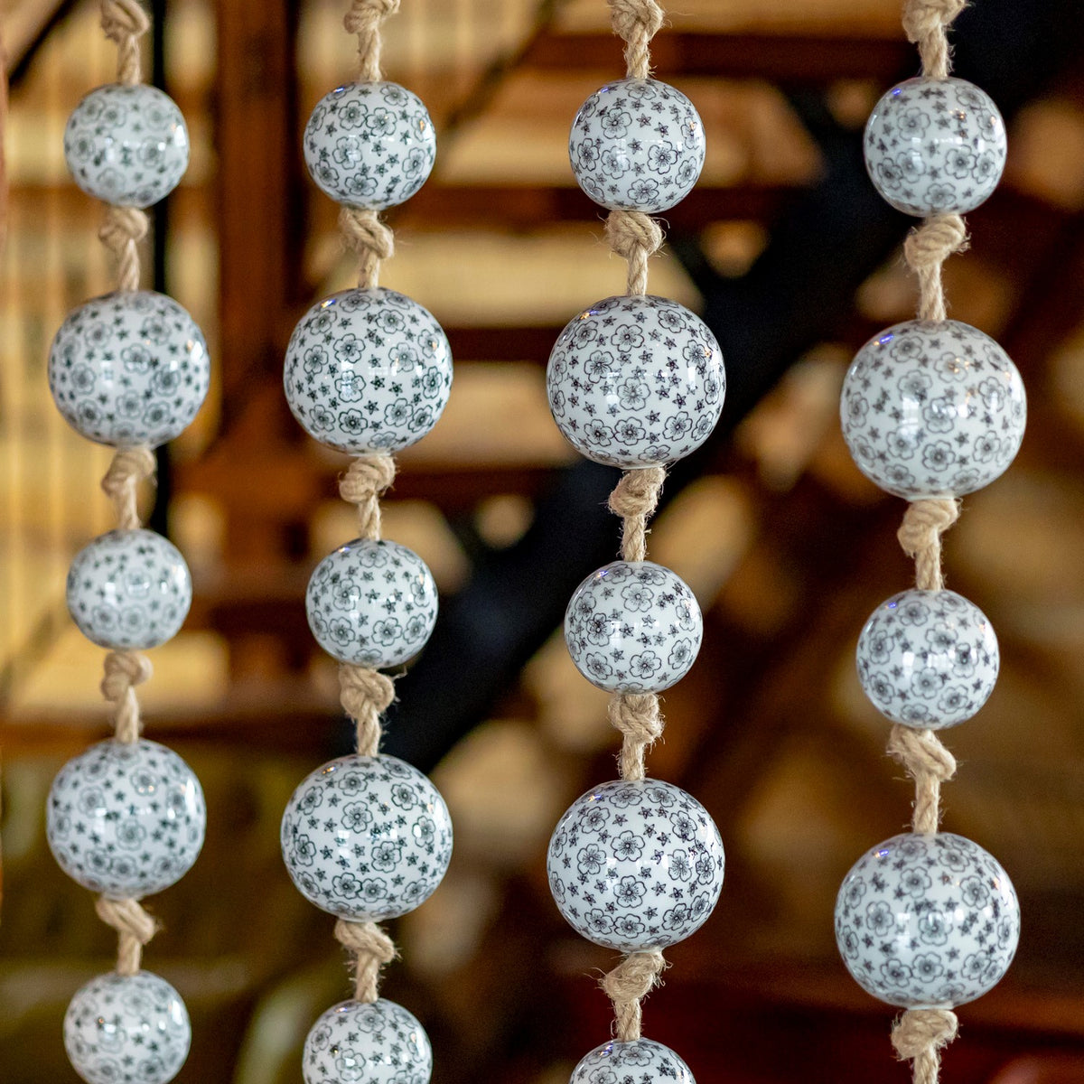 Vertical jute cords display rows of white balls with fine dark floral patterns.