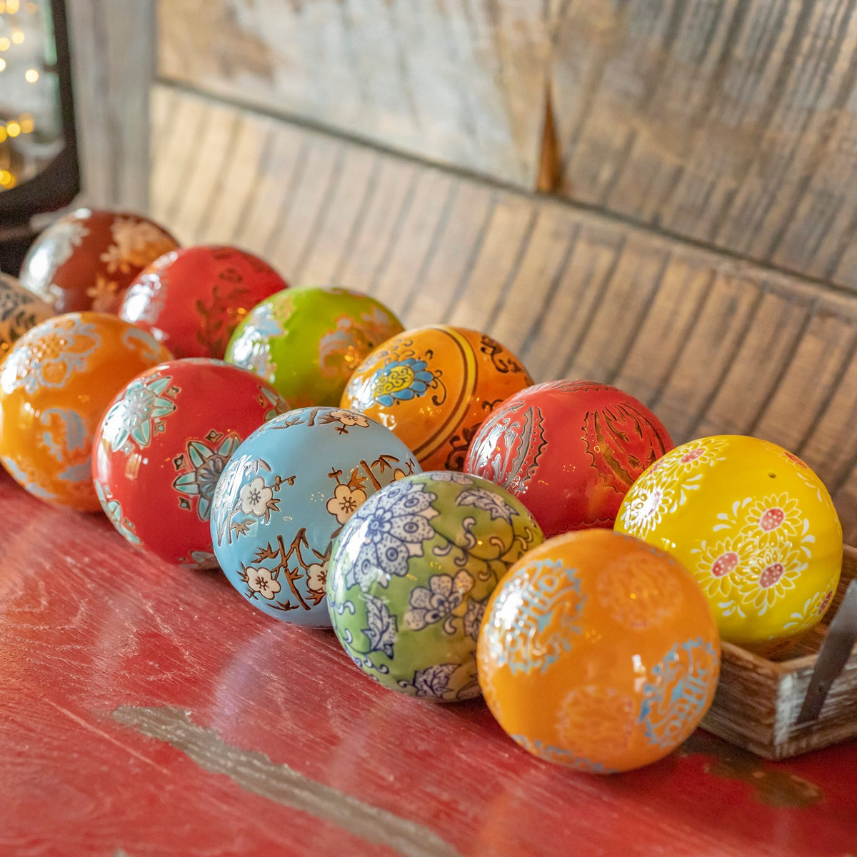 Brightly colored patterned ceramic balls arranged in a wooden tray.