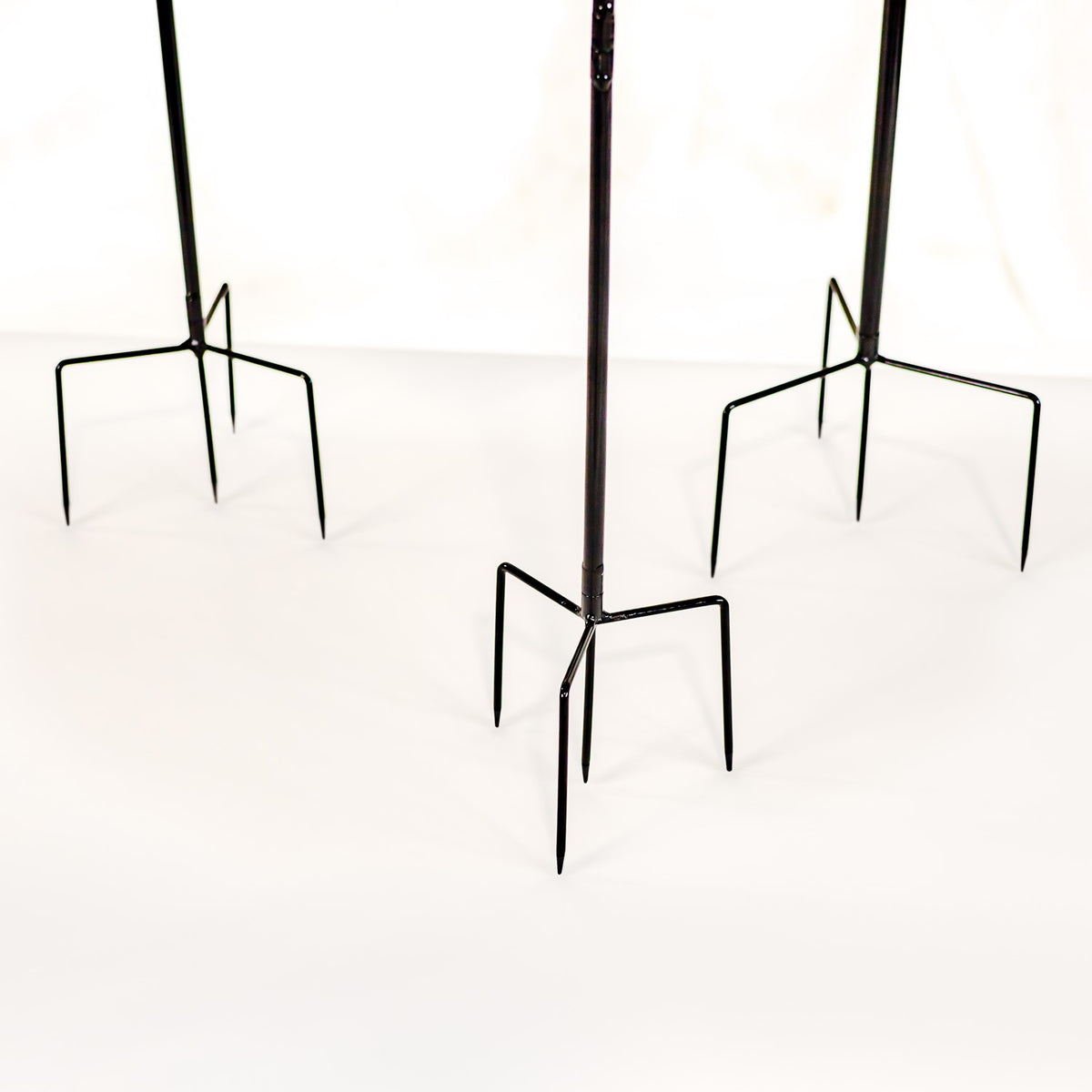 Three black metal garden stakes with pointed, four-pronged bases shown against a white background.