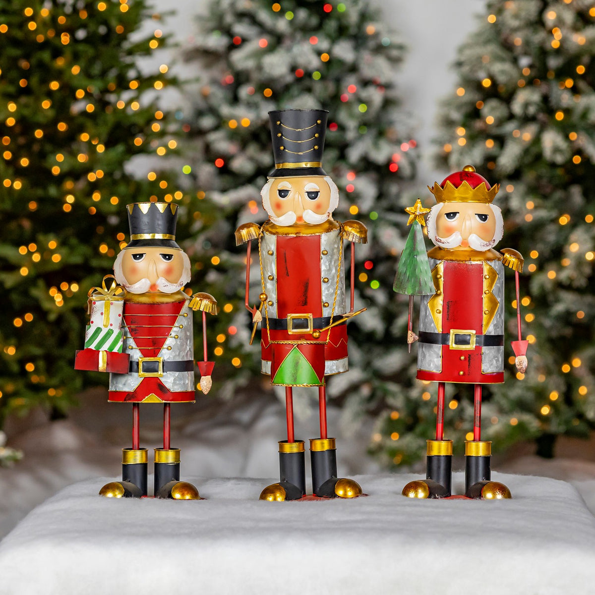 Three metal nutcracker figurines displayed together, including one with a Christmas tree