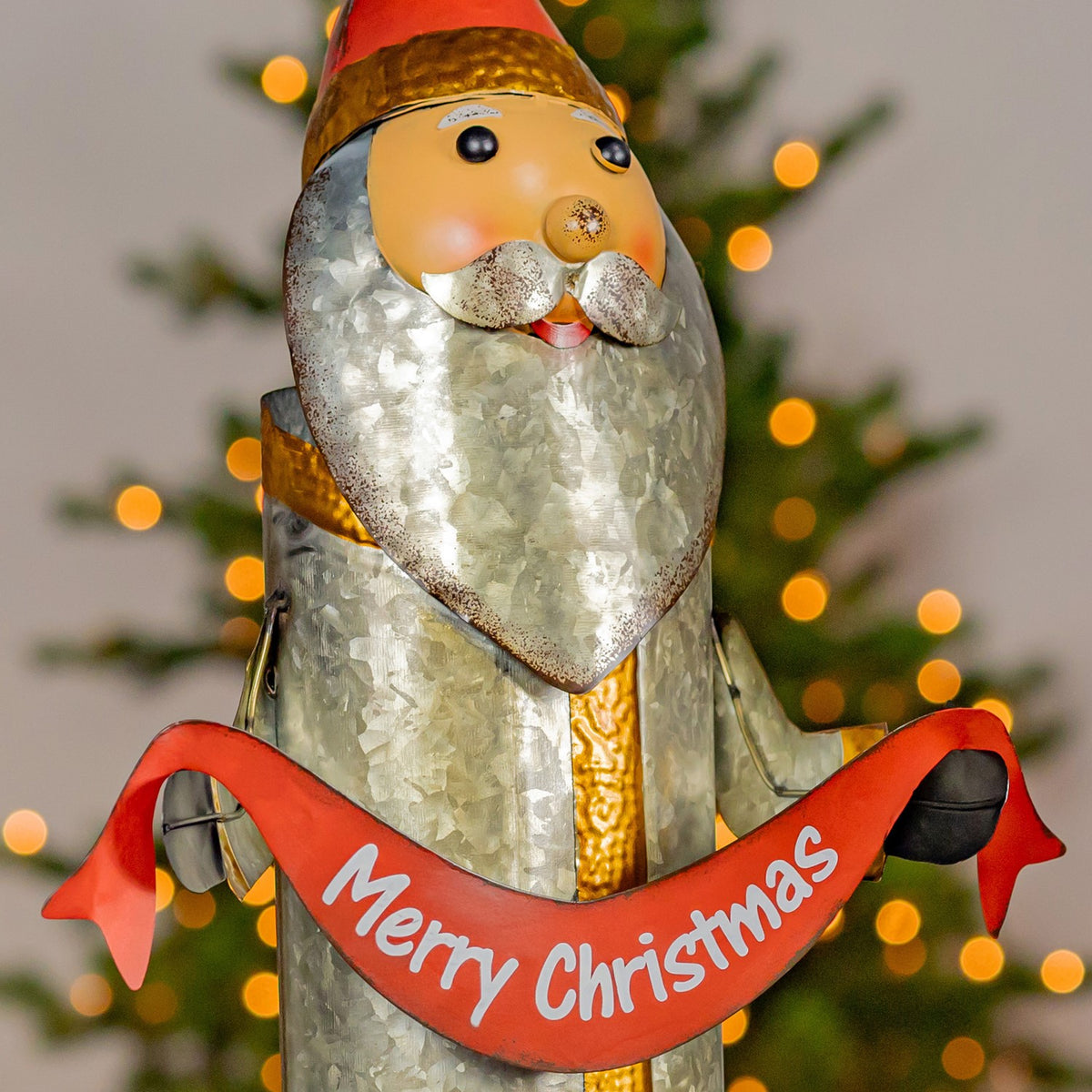 Angled close view of Santa holding a red Merry Christmas sash