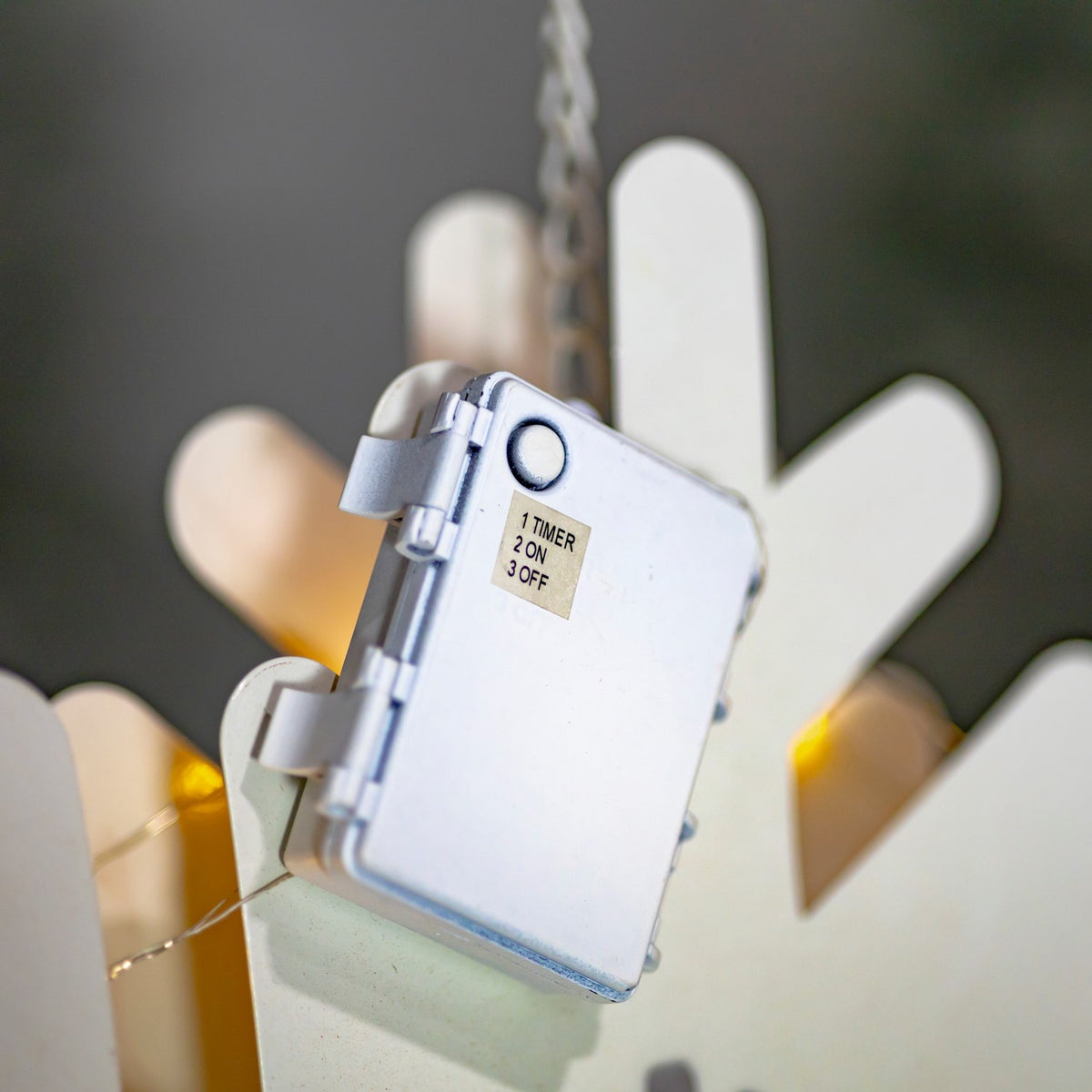 Close-up of the back of a hanging snowflake showing its attached battery pack
