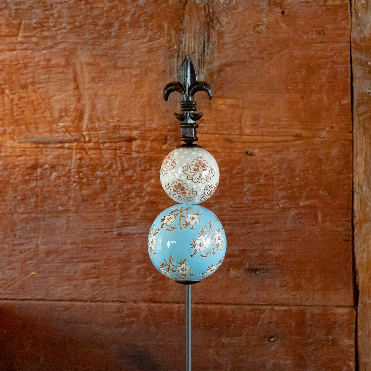 Cream and light blue floral ceramic spheres on an iron garden stake